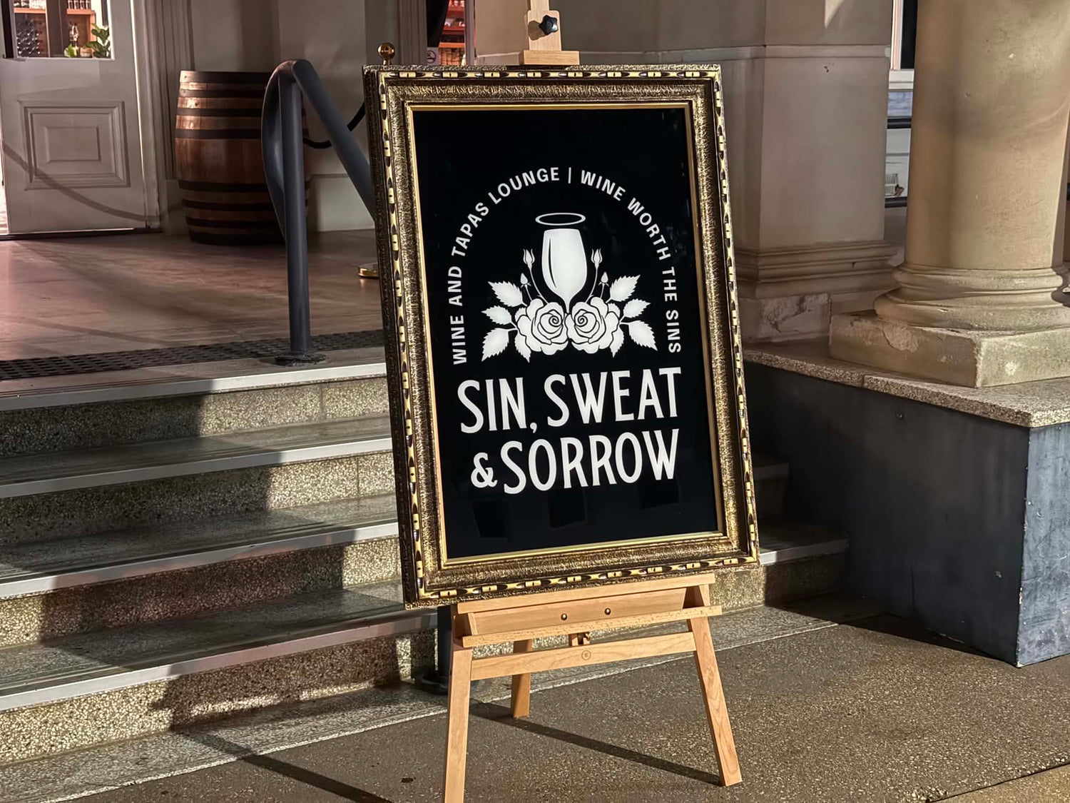 Decorative sign on an easel with text and graphics, placed outdoors.